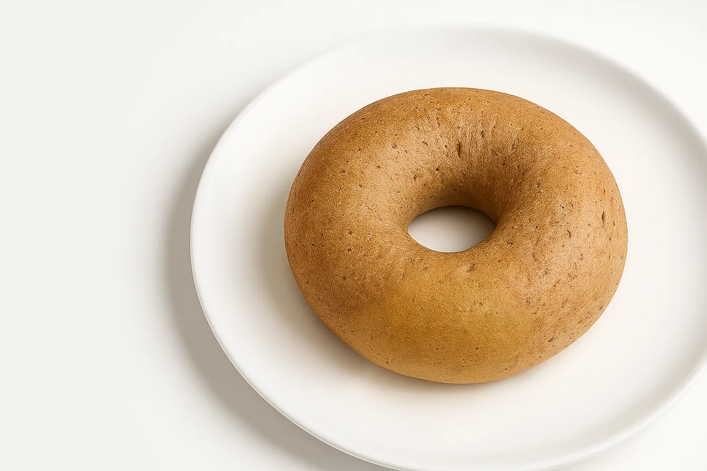 A plain bagel with no toppings, on a white plate.